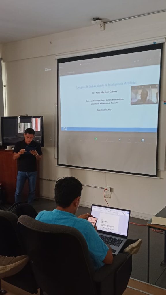 Proyección de la presentación titulada “Lengua de Señas desde la Inteligencia Artificial” del Dr. Niels Martínez Guevara, con asistentes en el auditorio siguiendo la ponencia.