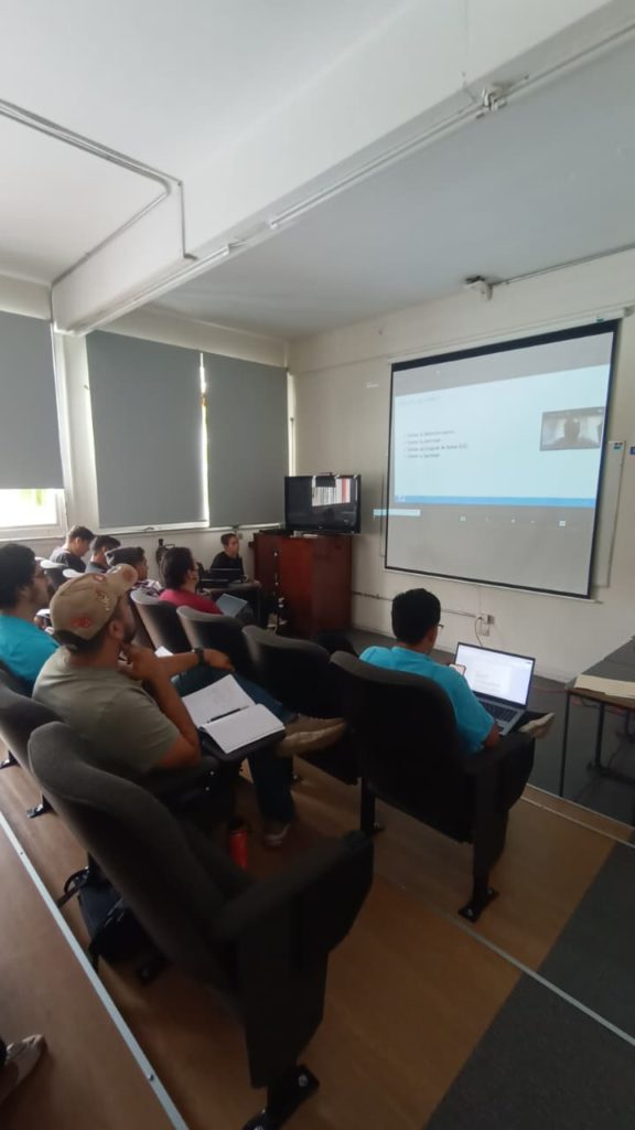 Estudiantes y asistentes en el auditorio de la Facultad de Estadística e Informática toman notas y siguen atentamente la ponencia proyectada en pantalla.